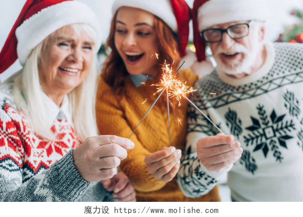 女人和爸爸妈妈放着烟花老两口带女儿在圣诞节点亮闪光灯的选择性焦点